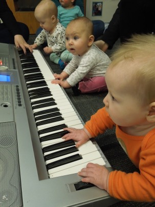 Infants playing a real piano during a unit on music.