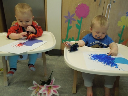 Infants learning about flowers explore painting with silk flowers. The sensation of touching and tasting is just as exciting as the experience of squishing the painted flowers onto the paper.